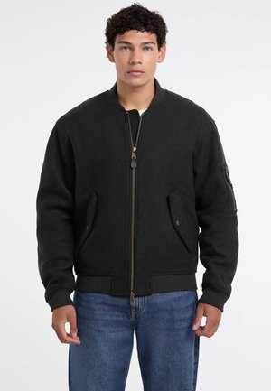 Giubbotto bomber nero realizzato in misto lana, con zip frontale, polsini a costine e tasche frontali inclinate con una tasca laterale con zip per riporre oggetti.