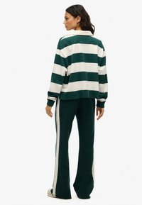 Groen en wit gestreepte pullover met kraag, gecombineerd met bijpassende wijde broek met zijkanten. Zachte stof en een relaxte fit.