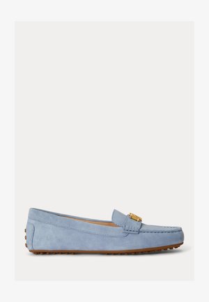 Vaaleansininen mokkanahkainen loafer, jossa kultainen metallisolki ja ruskea kuminen kivitassu-pohja, esitetty sivuprofiilissa.