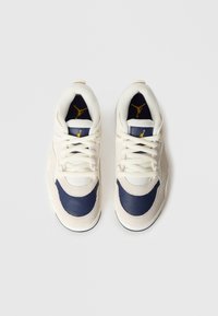 Μπεζ και ναυτικά αθλητικά παπούτσια από δέρμα και ύφασμα, με επενδυμένη γλώσσα, κορδόνια και χρυσό λογότυπο σε ναυτικό φόντο.