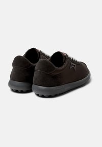 Black sneakers featuring a mix of smooth leather and suede materials, rounded shape, and textured rubber sole with visible traction.