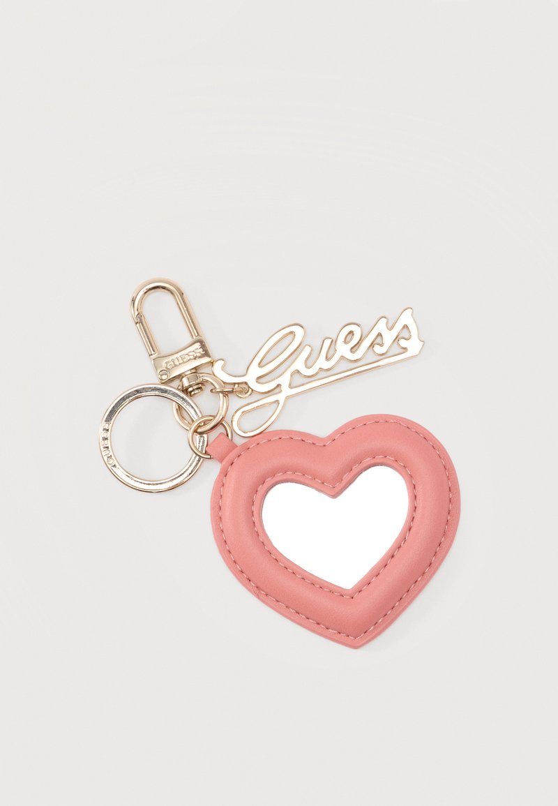 Ροζ μπρελόκ σε σχήμα καρδιάς με μικρό καθρέφτη στο κέντρο, χρυσό μενταγιόν με το λογότυπο "Guess" και χρυσό κούμπωμα για τα κλειδιά.