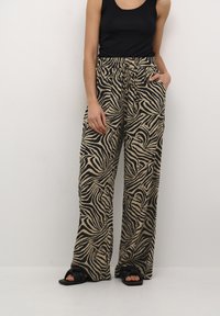 Pantalons large à motif zèbre en tissu beige et noir avec une taille élastique, dotés de poches latérales et d'une coupe décontractée.