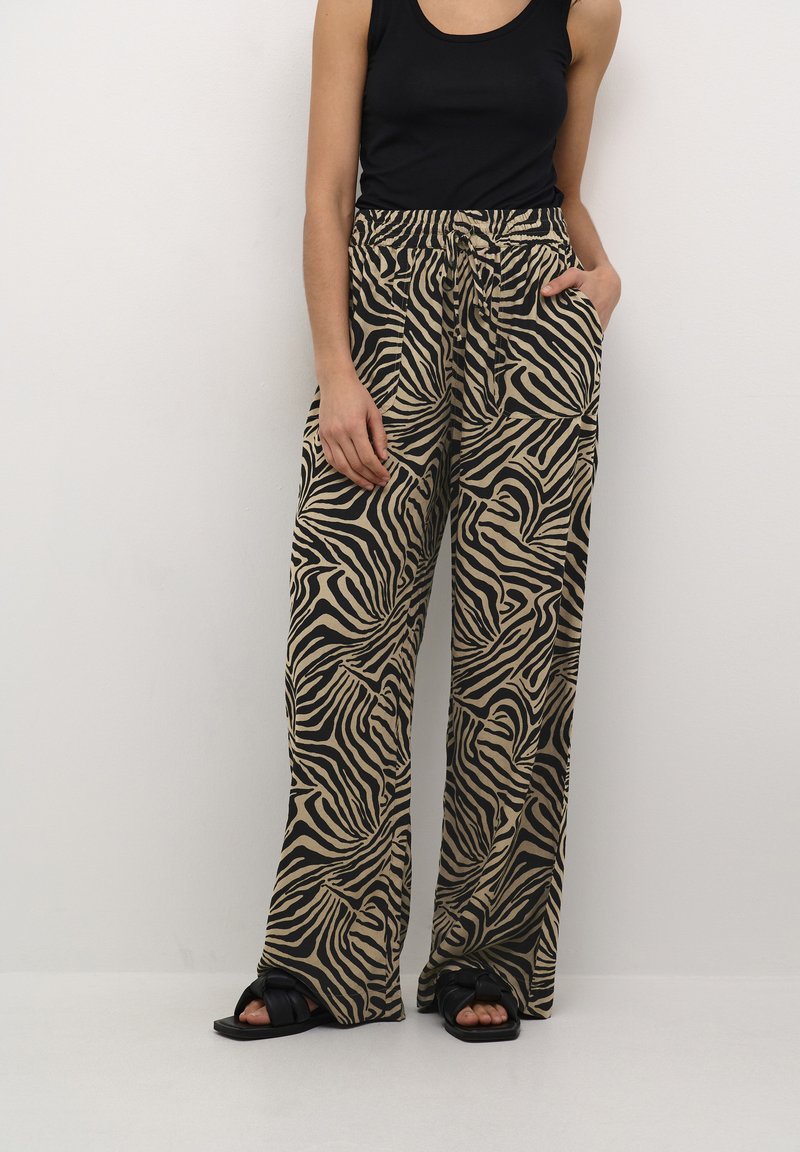 Pantalons large à motif zèbre en tissu beige et noir avec une taille élastique, dotés de poches latérales et d'une coupe décontractée.