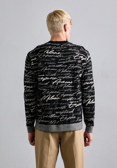 Schwarzer Pullover mit einem strukturierten Schriftmuster in Weiß, grauem geripptem Saum und Bündchen, sichtbaren Nähten und lässiger Passform.