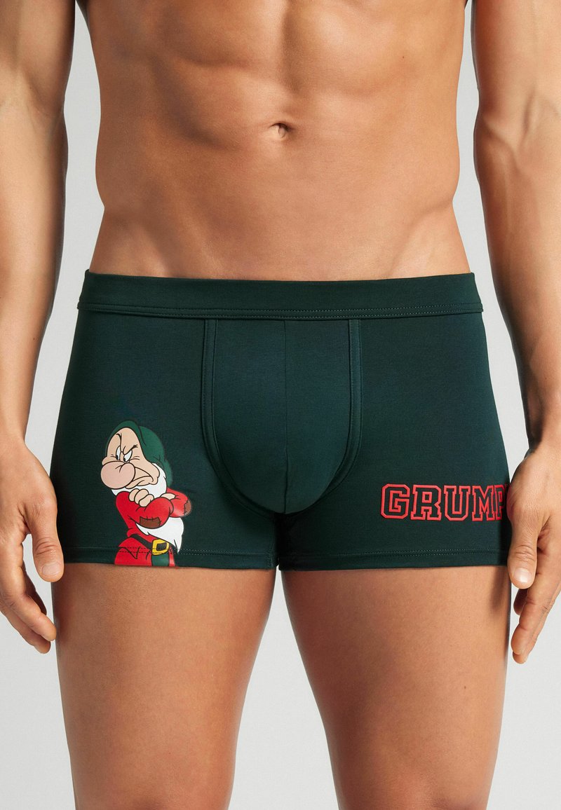 Donkergroene boxers gemaakt van zachte stof met een cartoonfiguur met een chagrijnige uitdrukking en het woord "GRUMP" in vetrode letters.