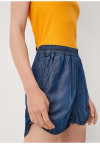 Pantaloni corti di jeans con vita elastica, caratterizzati da una vestibilità comoda e tasche laterali. Il tessuto presenta una trama blu sbiadita.