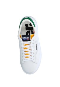 Zapatilla blanca con detalles amarillos y cordones blancos. Presenta un collar de talón verde y detalles laterales perforados. Marca en la lengüeta.