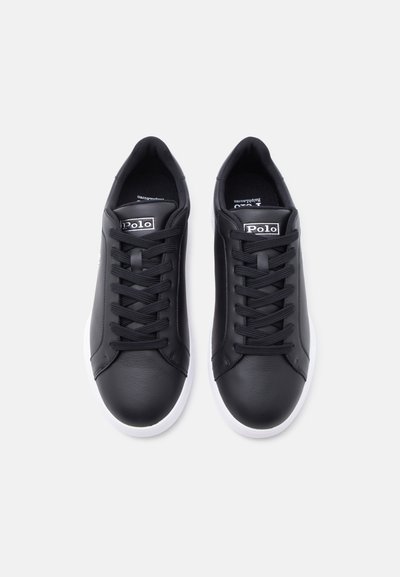 Μαύρα αθλητικά παπούτσια Polo χαμηλού ύψους με λευκές σόλες, μαύρα κορδόνια και το λογότυπο Polo στη γλώσσα, εμφανιζόμενα από πάνω σε λευκό φόντο.