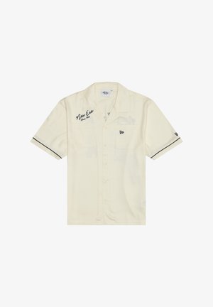 Kremfarvet kortærmet skjorte med knapper, med teksten "New Era Since 1920" på brystet, to forlommer og sort kant på ærmerne.