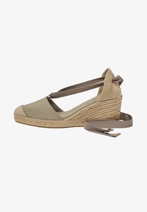 Espadrille compensée beige avec semelle en jute tissé et liens à nouer autour de la cheville, dotée d'un bout fermé et d'un contrefort de talon texturé.