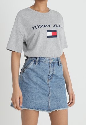 Harmaa puuvillapaita, jossa on "TOMMY JEAN" -teksti ja logo. Yhdistetty sinisiin farkkuhameeseen, jossa on risat helmat ja etutaskut.
