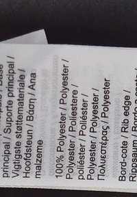 Etiqueta con texto sobre el cuidado de la tela y material. Hecha de 100% poliéster con varios idiomas mostrados. Sin gráficos ni detalles adicionales.