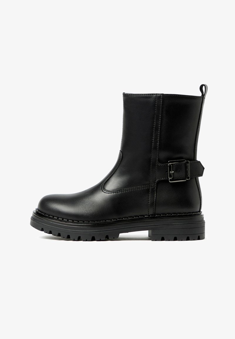 Bottines en cuir noir avec un embout arrondi, un panneau élastique sur le côté et un détail de boucle sur la sangle de la cheville. Semelle en caoutchouc rainurée pour une meilleure adhérence.