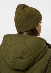 Berretto lavorato a maglia verde oliva con texture a coste, abbinato a un giubbotto trapuntato verde oliva con cuciture diagonali e cappuccio.