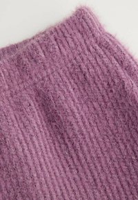 Fioletowa dzianina o miękkiej, puszystej fakturze. Charakteryzuje się pionowym prążkowanym wzorem i subtelnym połyskiem dzięki wplecionym włóknom.