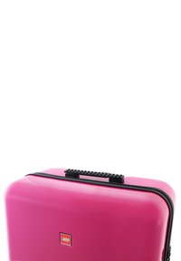 Pink hard-shell LEGO carrying case with a textured black handle, smooth surface, and black zipper. Features a small LEGO logo on the front.