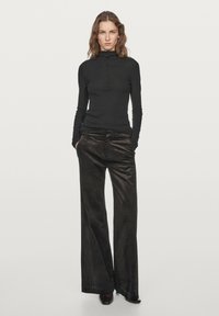 Black long-sleeve turtleneck top with a slim fit, paired with wide-leg dark brown corduroy pants. The fabric has a soft texture.