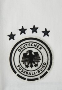 Μαύρο και άσπρο κυκλικό λογότυπο με ένα αετό, περιτριγυρισμένο από το κείμενο "DEUTSCHER FUSSBALL-BUND" και τέσσερις μαύρους αστερίσκους από πάνω.