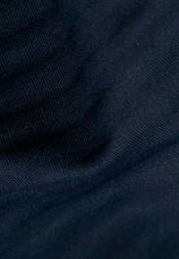 Dunkelblauer Stoff mit einer feinen, strukturierten Webart. Glatte Oberfläche mit dezenter Glanzbildung und sanften Falten, die Weichheit und Flexibilität anzeigen.