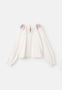 White long-sleeve blouse with a textured finish, featuring a keyhole neck and red embroidered accents on shoulders. Soft, loose fit.