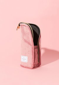 Rosa fløyels pennal med gullglidelås, har en frontlomme og svart innervattering. Merketittel på siden.