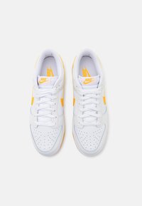 Białe skórzane sneakersy z żółtymi akcentami, z perforowanym noskiem, klasycznym wiązaniem na sznurówki i gumową podeszwą. Logo marki na języku.