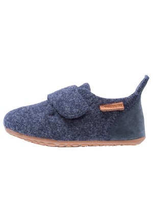 Chaussure bébé bleu marine douce avec une large bride velcro, semelle en caoutchouc marron, talon en daim, et une petite étiquette en cuir cousue sur le côté.