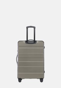 Tvrdý cestovní kufr v kovově šedé barvě s horizontálními žebry, černou vysouvací rukojetí a čtyřmi černými koly pro snadnou mobilitu.