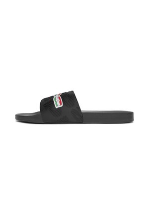 Sandalia tipo slide negra con una correa ancha con patrones en relieve y un logo tricolor (verde, blanco, rojo) en la parte superior.