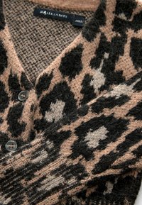Strickjacke im rosa und schwarzen Leopardenmuster mit V-Ausschnitt, Knöpfen und einer weichen, strukturierten Oberfläche. Markenetikett sichtbar.