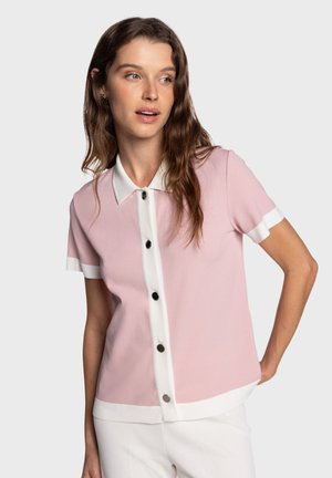 Polo a maniche corte in tessuto rosa chiaro con collo bianco e patta con bottoni, caratterizzata da bottoni neri e polsini bianchi a contrasto.