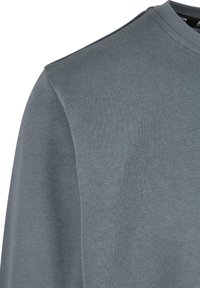 Sweat-shirt gris foncé à col rond avec col côtelé et tissu en coton lisse visible sur l'épaule et le haut de la manche.