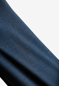 Ciemnoniebieska teksturowana tkanina o subtelnym wzorze splotu, charakteryzująca się miękką, gładką powierzchnią i jednolitym kolorem na całej powierzchni.