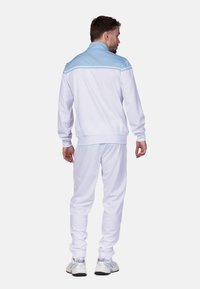 Weißer Trainingsanzug mit hellblauen Akzenten, ausgestattet mit einem Reißverschlusskragen und gerippten Bündchen. Das Material wirkt glatt und sportlich.