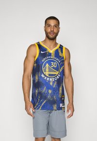 Golden State Warriors-drakt, blå med gule aksenter, har en bro-logo og spiller nummer 30. Laget av pustende stoff med en jevn tekstur.