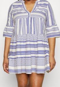 Blå och vit randig klänning med V-ringning, utsvängda ärmar och en utsvängd kjol, med geometriska mönster och texturerad tyg.