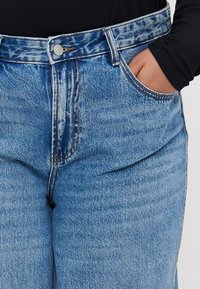 Lichtblauwe denim jeans met een hoge taille, voorzien van een knoopsluiting, voorzakken en zichtbare stiksel-details.
