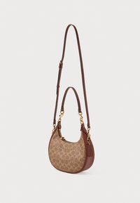Smeđi kožni crossbody torba s zlatnim hardverom, koja ima prepoznatljiv logotip u bež boji i zaobljen oblik s kratkim remenom.