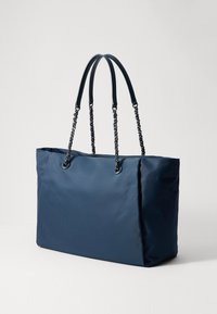 Granatowa, duża torba na ramię z podwójnymi paskami, ozdobiona metalowymi ogniwami łańcucha i skórzanymi akcentami, wyeksponowana na białym tle.