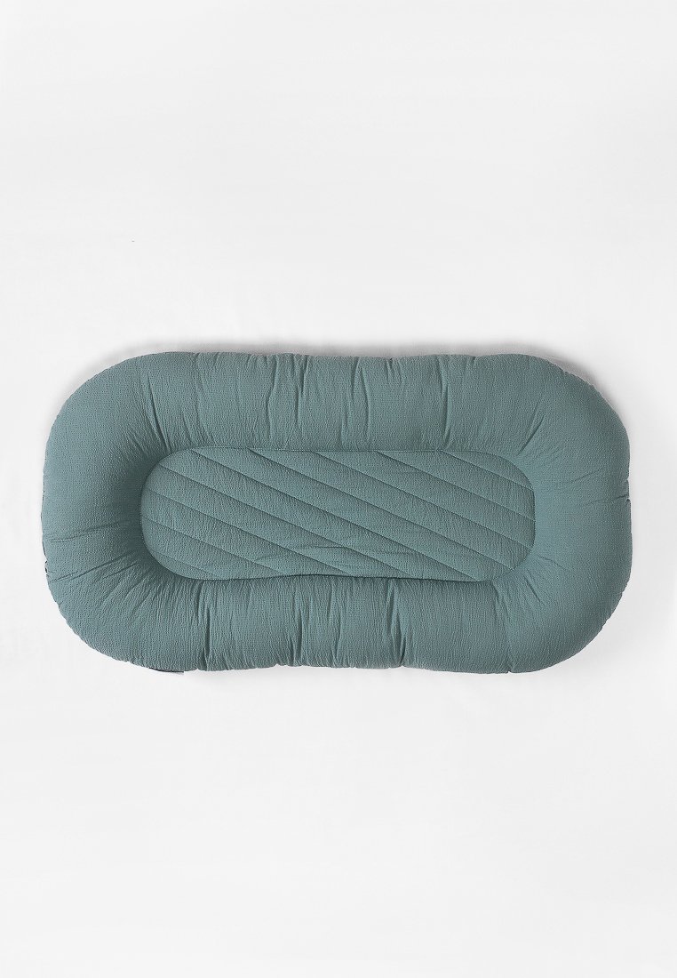Lit pour animal de compagnie rectangulaire en tissu teal doux. Texture matelassée avec bords surélevés pour un soutien. Centre lisse et rembourré avec un détail de couture subtile.