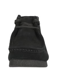 Zapato de ante negro con puntera redondeada, detalle de costura a lo largo del borde y suela de goma texturizada; cuenta con un diseño de cordones con cordones planos.