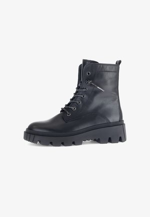 Botte chelsea en cuir noir à lacets avec une semelle à crampons épaisse, bout rond, accents métalliques et col rembourré pour un confort supplémentaire.