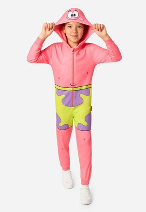 Enfant portant une grenouillère rose avec un motif short vert et violet et une capuche ornée d'un visage de dessin animé, tenant les bords de la capuche levés.