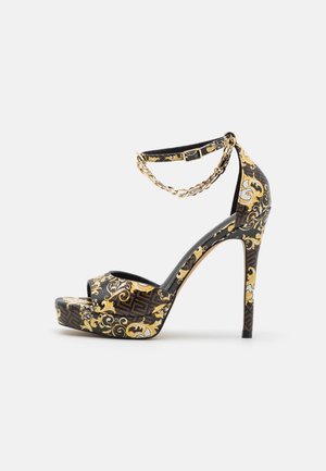 Høje hæle platform sandal med et sort og guld udsmykket mønster, åben tå-design, justerbar ankelrem og stiletto-hæl.