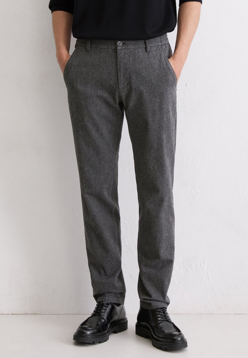 Gray wool-blend trousers with a straight cut, featuring a button closure, side pockets, and a textured fabric finish. Worn with black shoes.