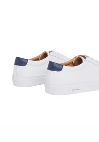 Weiße Sneakers mit marineblauen Fersenakzenten, ausgestattet mit einem glatten Leder-Obermaterial, einer abgerundeten Zehenpartie und einer strukturierten Gummisohle, minimaler Branding.