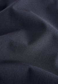 Černá tkanina s hladkou texturou, vykazující jemné záhyby a subtilní lesk, což vytváří bohatou vizuální hloubku bez výrazných vzorů.