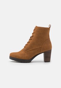 Bottines en daim marron avec un talon bloc haut, un devant lacé et des détails de couture sur les côtés. Semelle texturée pour une meilleure adhérence.