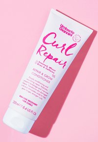 Krulrepair conditioner in een witte tube met roze accenten. Met opvallende tekst die ingrediënten zoals zeewier en cafeïne vermeldt. 250ml, cruelty-vrij.